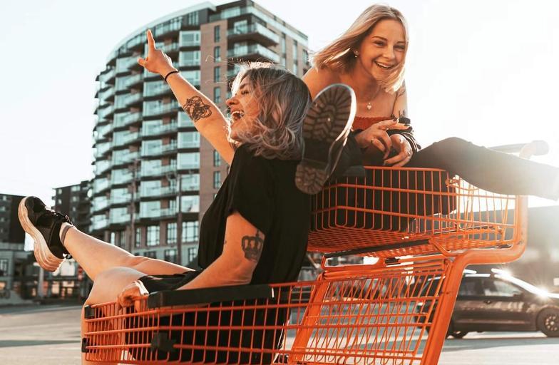 Two girls laughing and riding in shopping carts