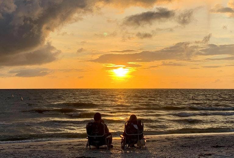couple on the beach sitting watching the sunset